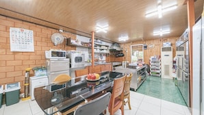 A kitchen with a brick wall, wooden cabinets, a refrigerator, and a dining table with chairs. - Jeju Healing Resort (Jeju City)
