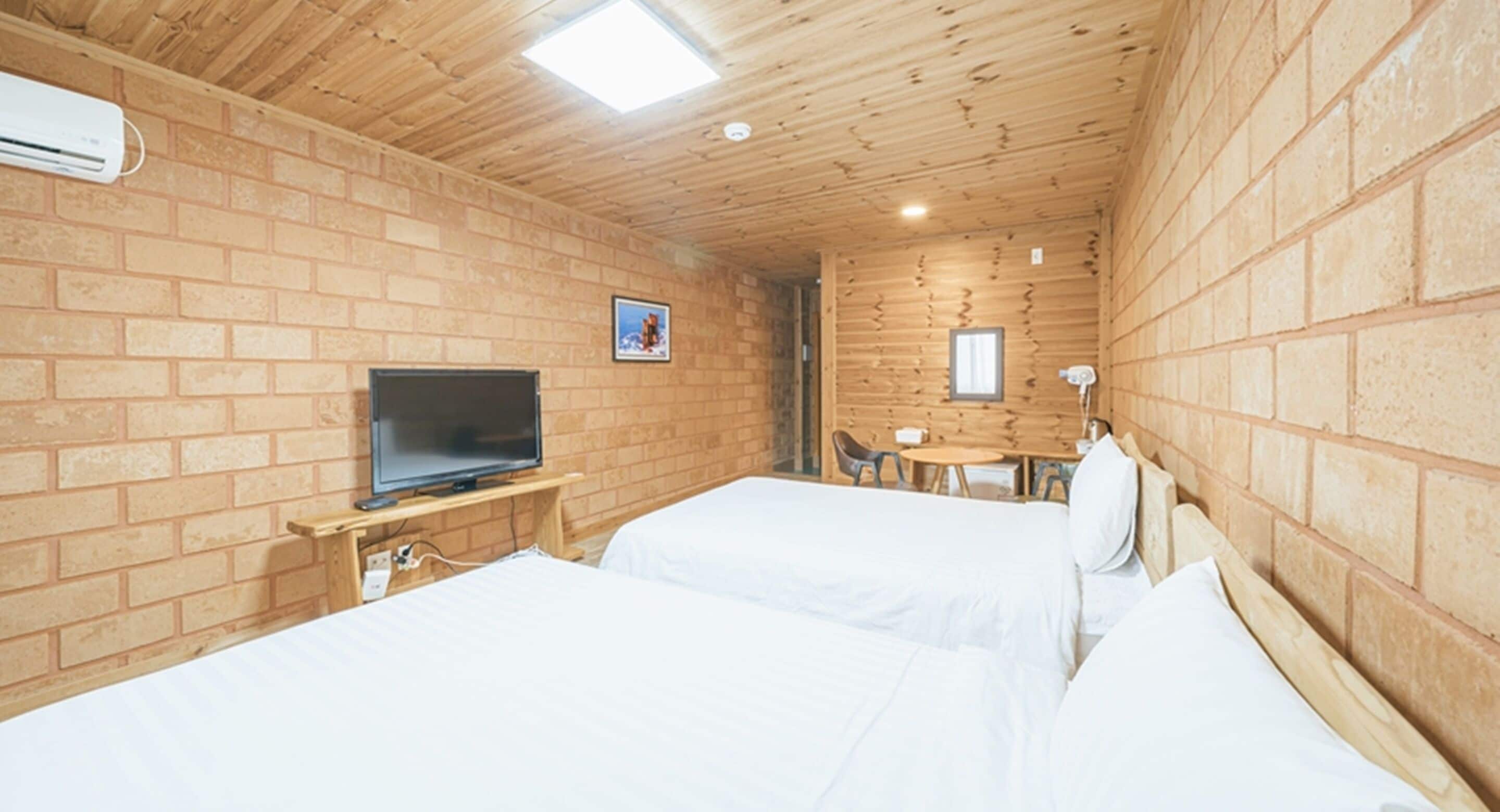 A room with two beds, a TV, a desk, and a small table.