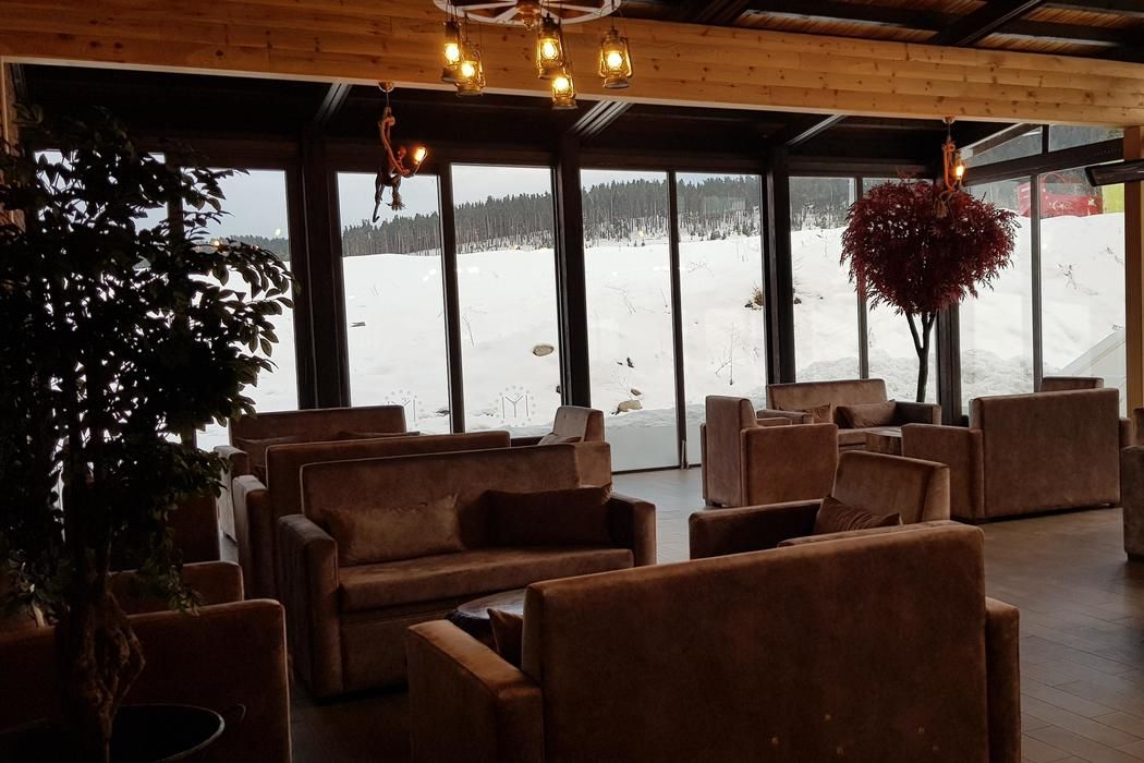 A cozy interior with sofas and a large window offering a snowy outdoor view.