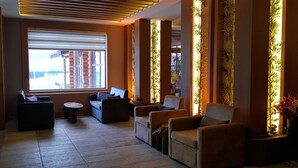Un salón moderno con un ventanal grande, asientos cómodos y paneles decorativos de bambú.