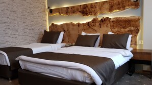 Habitación de hotel con dos camas, una pared de ladrillo y un cabecero de madera con iluminación integrada.