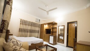 Une chambre d’hôtel comprenant un lit, un canapé, une table basse, une télévision et une armoire.