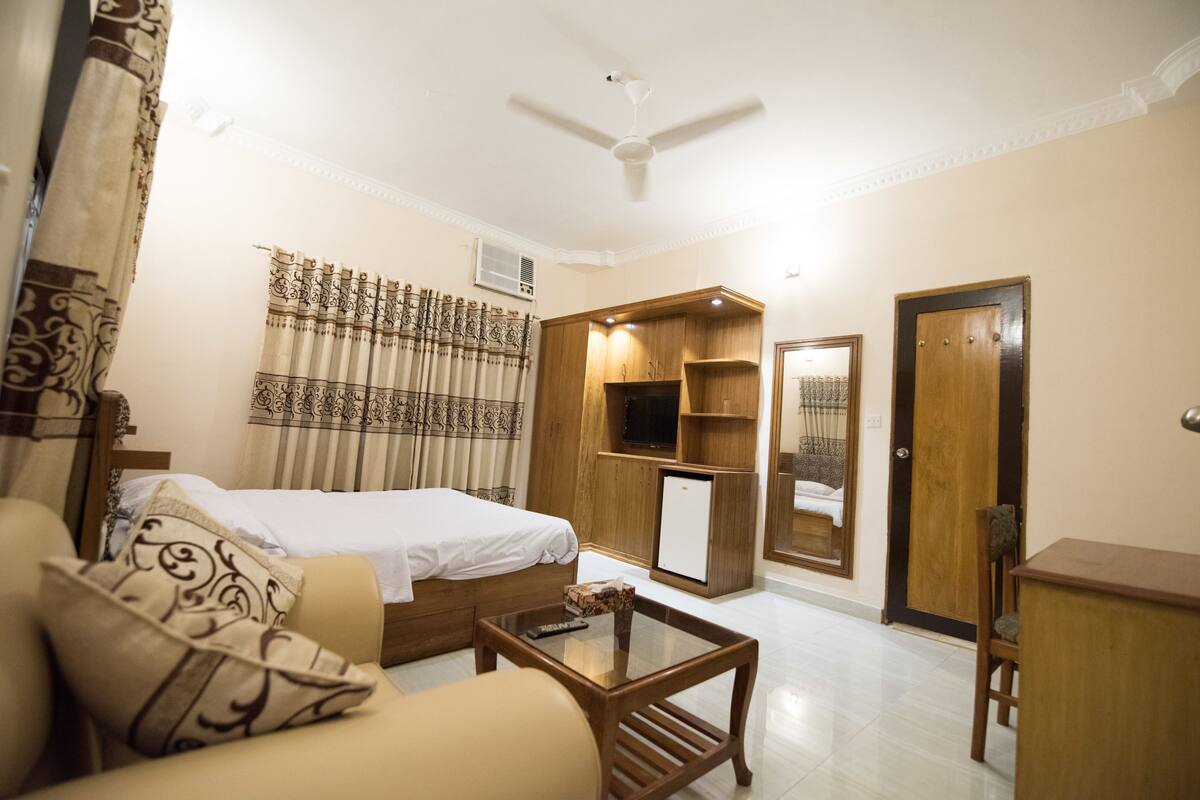 Une chambre d’hôtel comprenant un lit, un canapé, une table basse, une télévision et une armoire.