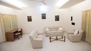 Un salon comprenant un ensemble de canapés, une table basse, un bureau en bois et un ventilateur de plafond.
