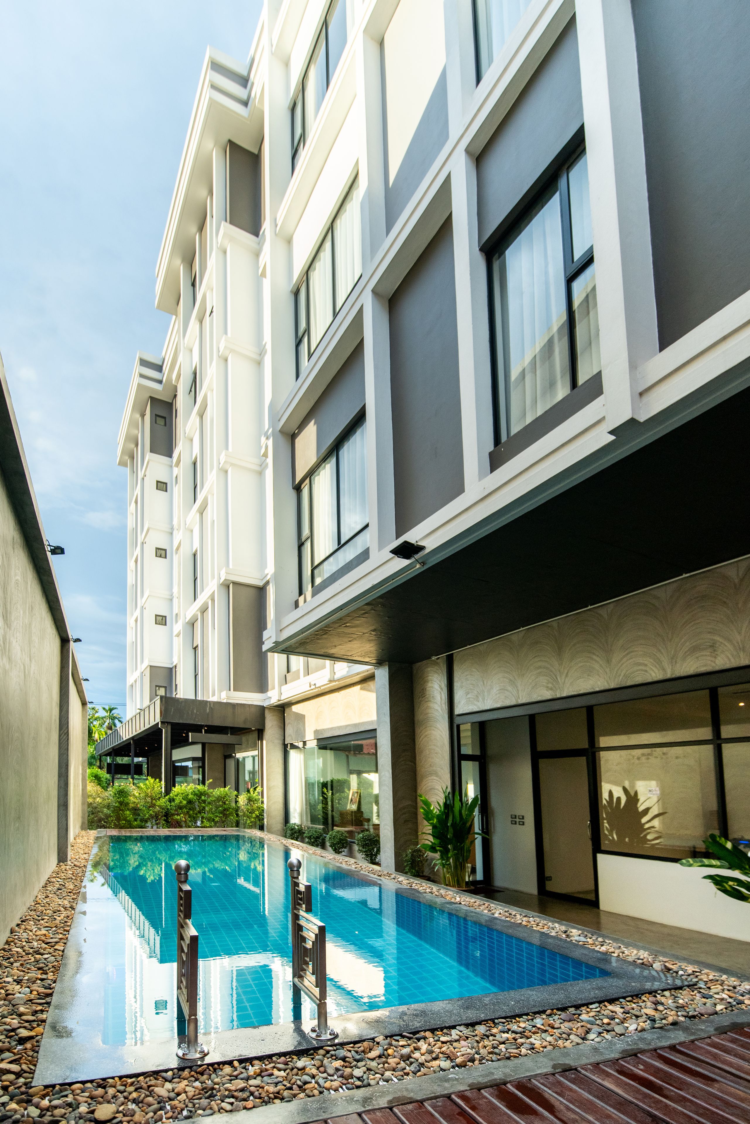 Um edifício moderno com piscina, rodeada por pedras e plantas.