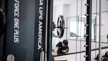 A gym with weightlifting equipment and a person exercising.