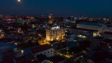 Overlooking the city, this building stands tall with illuminated windows and a rooftop sign.