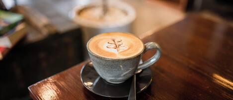 A cup of coffee with latte art on a saucer on a wooden table.