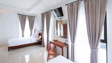 Una habitación de hotel con cama, escritorio, silla, televisor y cortinas.