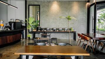 Un café moderno con una mesa y sillas de madera, una barra con una máquina de café y un muro con diseño.
