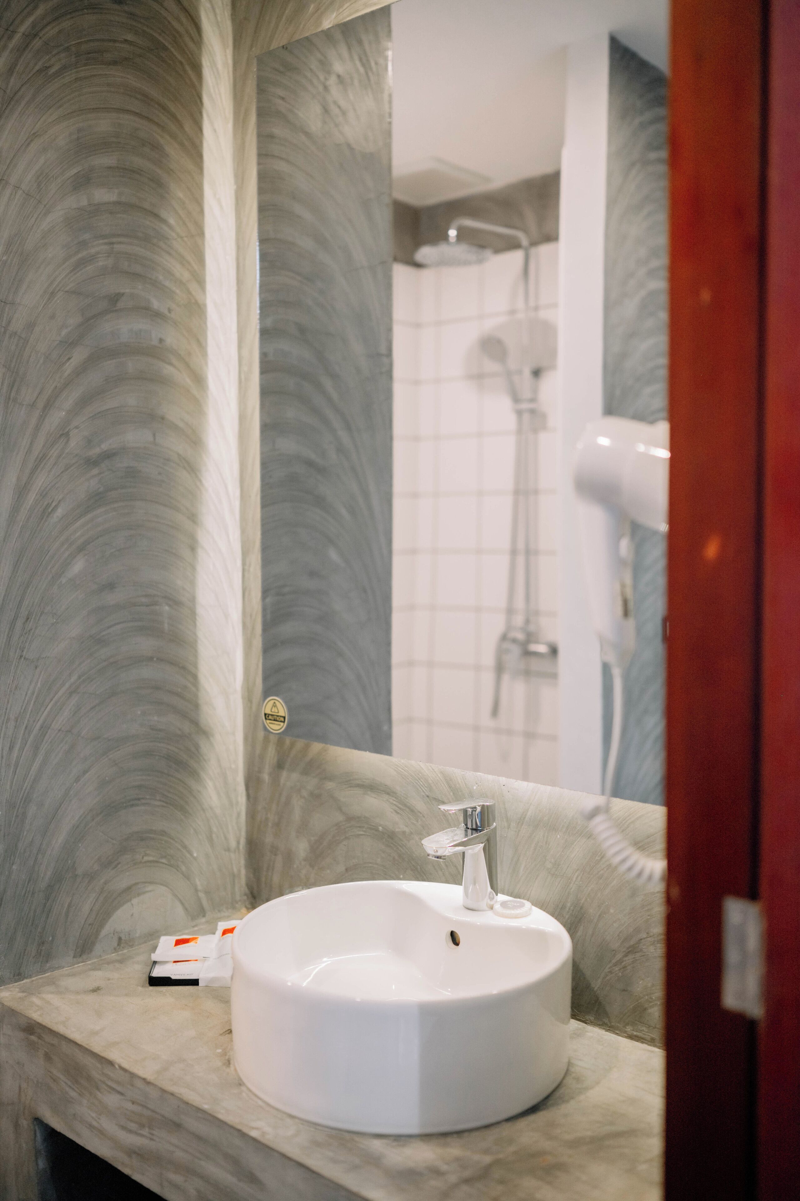 Ein Badezimmer mit einem runden weißen Waschbecken, einem Handtuchspender und einer Duschbrause.