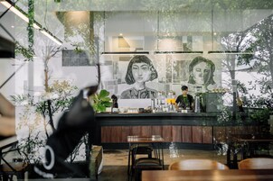 A modern cafe with a large mural, wooden furniture, and indoor plants.