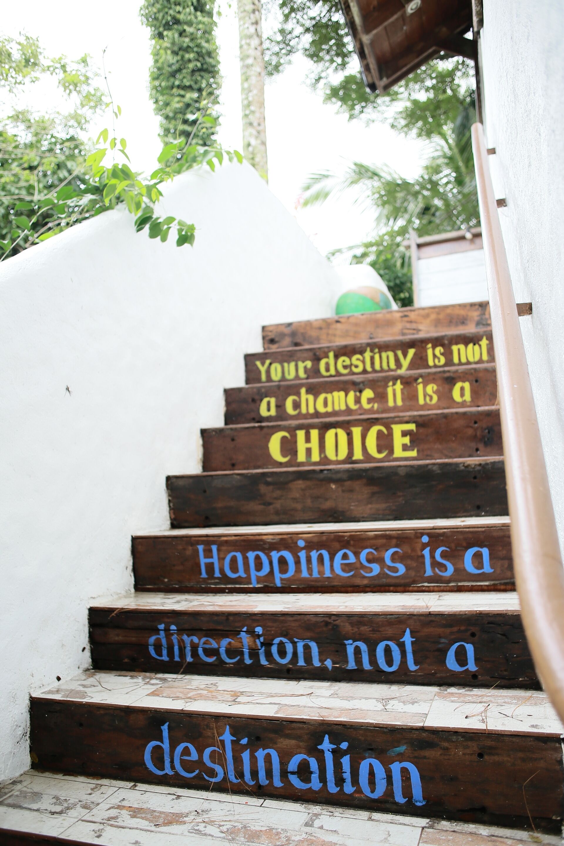 Una escalera de madera con citas motivacionales pintadas en los peldaños.