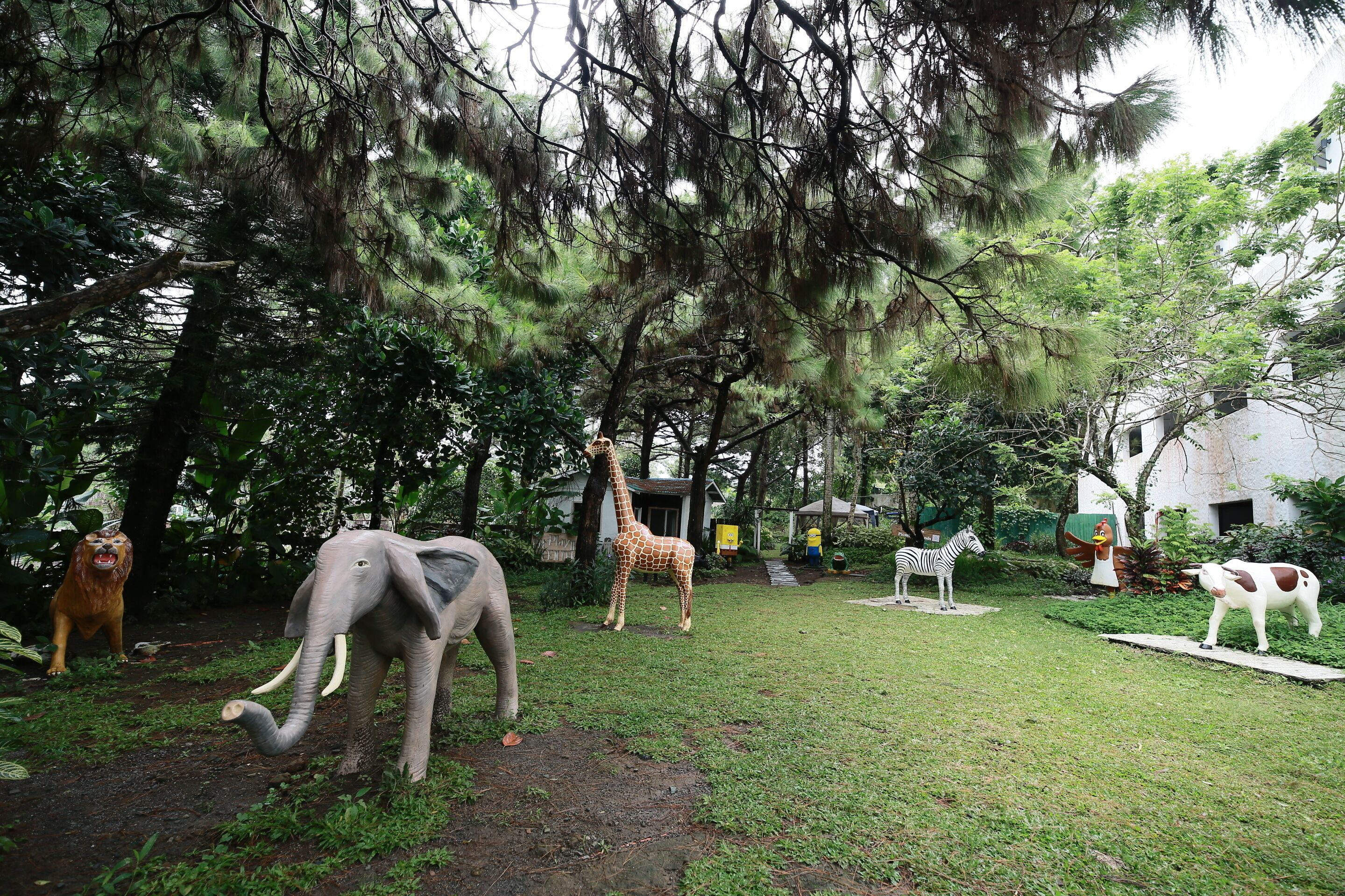 A garden with various animal sculptures, including elephants, giraffes, lions, and a zebra.