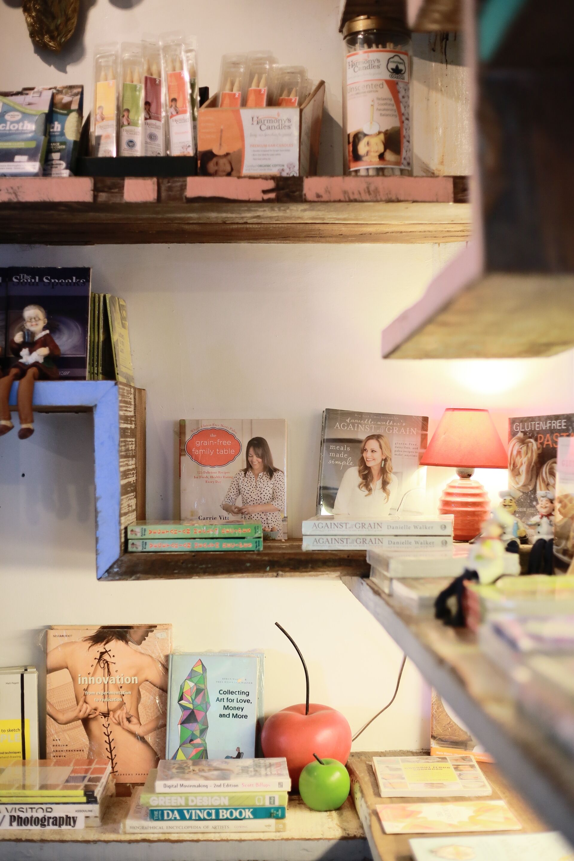 Una estantería con varios libros, velas y una figurita.