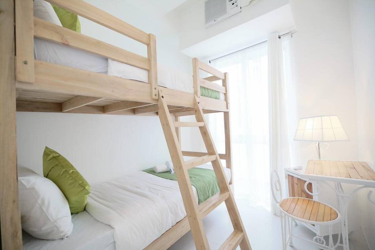 Una litera con escalera, una mesita con silla y una lámpara.