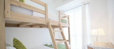Un lit superposé avec une échelle, une petite table avec une chaise et une lampe.
