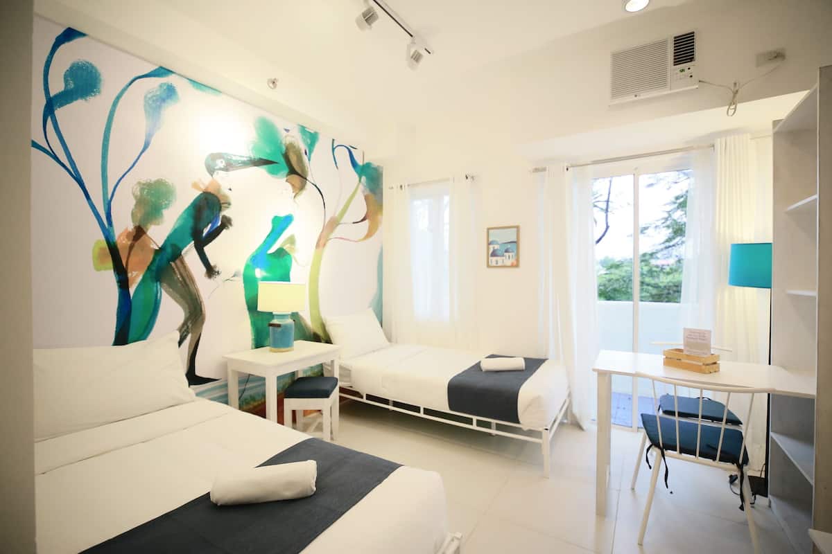 Een hotelkamer met twee bedden, een bureau en een groot abstract schilderij aan de muur.