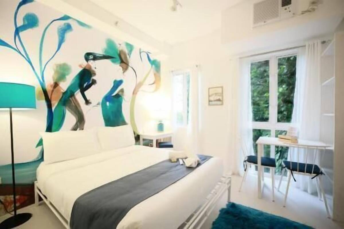Um quarto com uma cama, uma escrivaninha e uma cadeira.