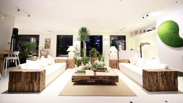 Uma sala de estar moderna com uma mesa de centro, dois sofás e um arranjo decorativo de plantas.