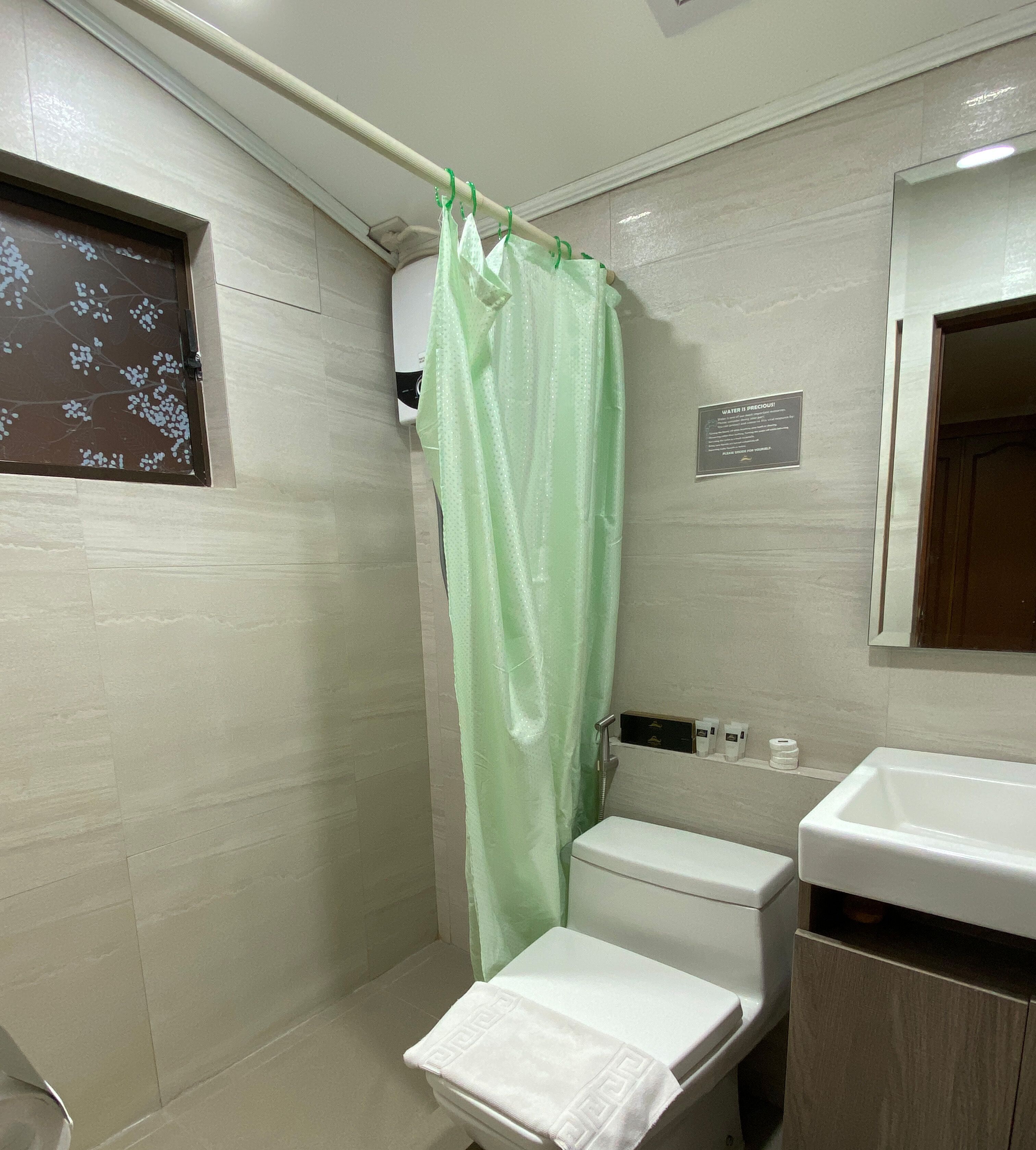 A bathroom with a shower curtain, toilet, sink, and a towel rack.