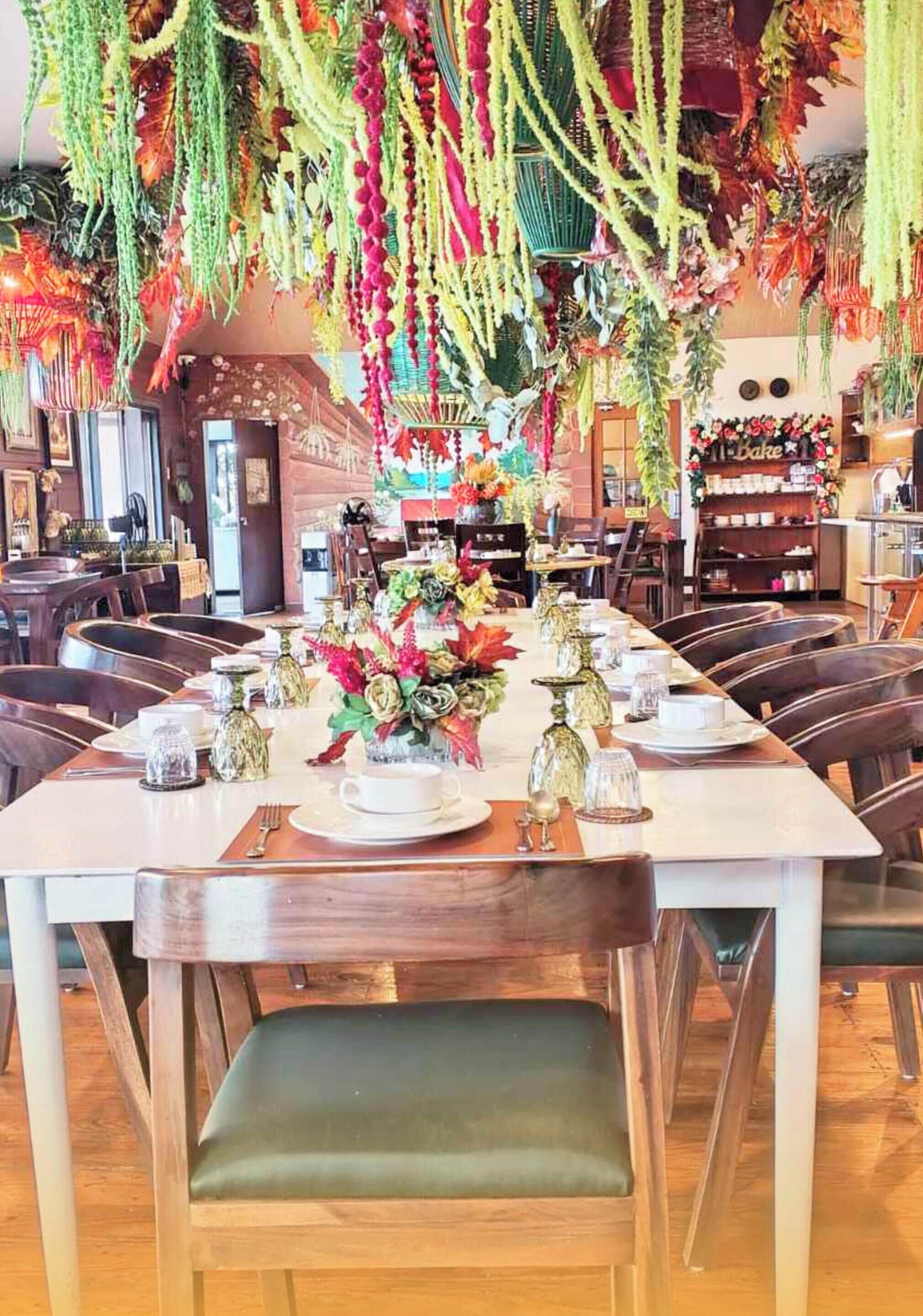 A restaurant with a long dining table set for a meal, surrounded by chairs.