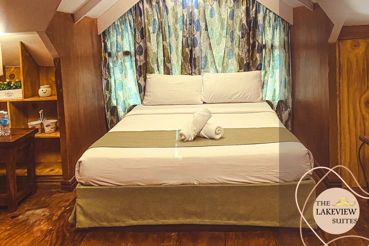Un dormitorio con una cama grande, cabecera de madera y cortina con estampado de hojas.