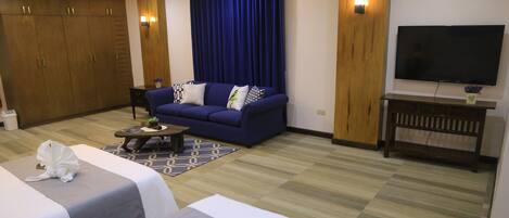 A hotel room with a sofa, two beds, a TV, and a wardrobe.