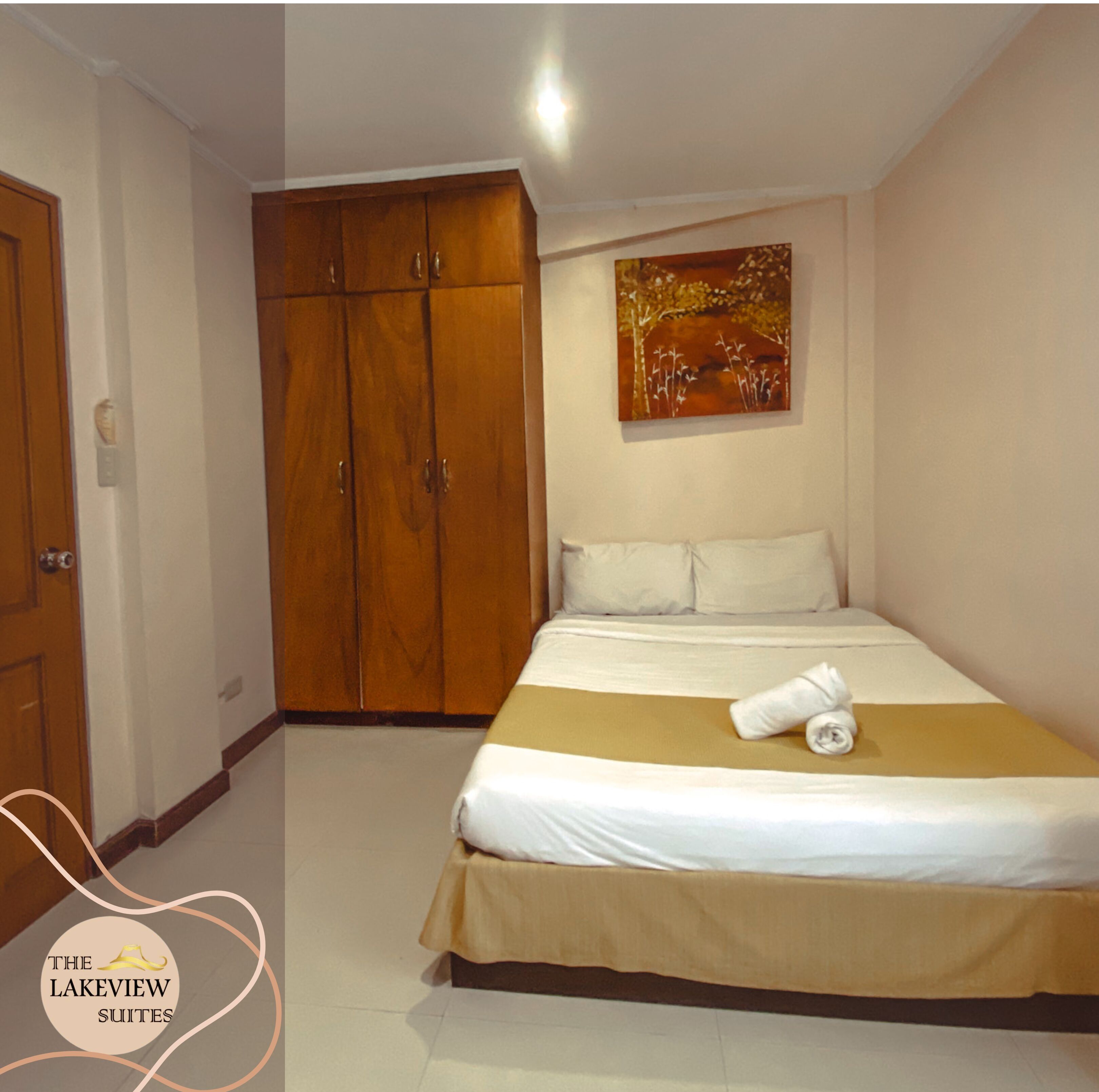 Una habitación de hotel con una cama, un armario de madera y un cuadro en la pared.