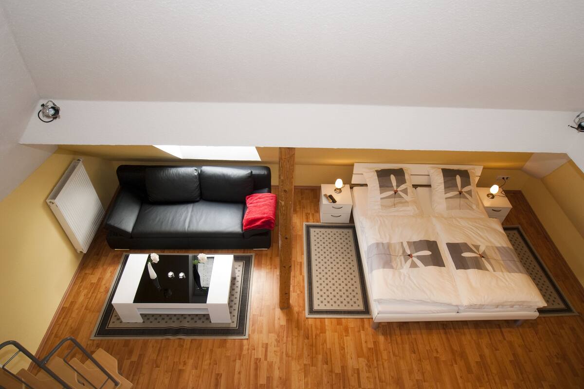 Un dormitorio acogedor con cama, sofá, una mesita pequeña y una mesita de noche.