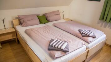A double bed with two pillows and a blanket, a bedside table, and a wall-mounted picture.