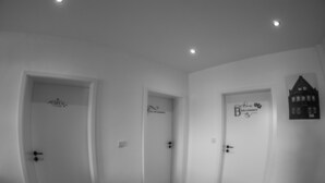 Un pasillo con tres puertas, cada una identificada con nombres y una pequeña decoración de casa.