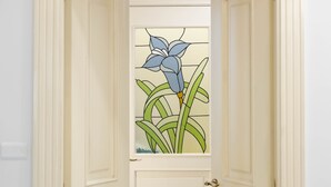 A hallway with cream-colored doors and a stained glass window with a blue flower. - B&B La Casa del Sole a Mergellina (Naples)
