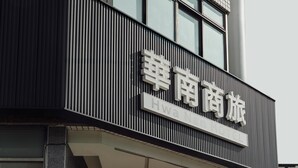 Un letrero de hotel con caracteres chinos y el texto en inglés 'Hwa Nan Hotel'.