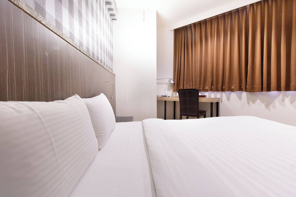 Une chambre d’hôtel avec un grand lit, un bureau et une fenêtre avec des rideaux.