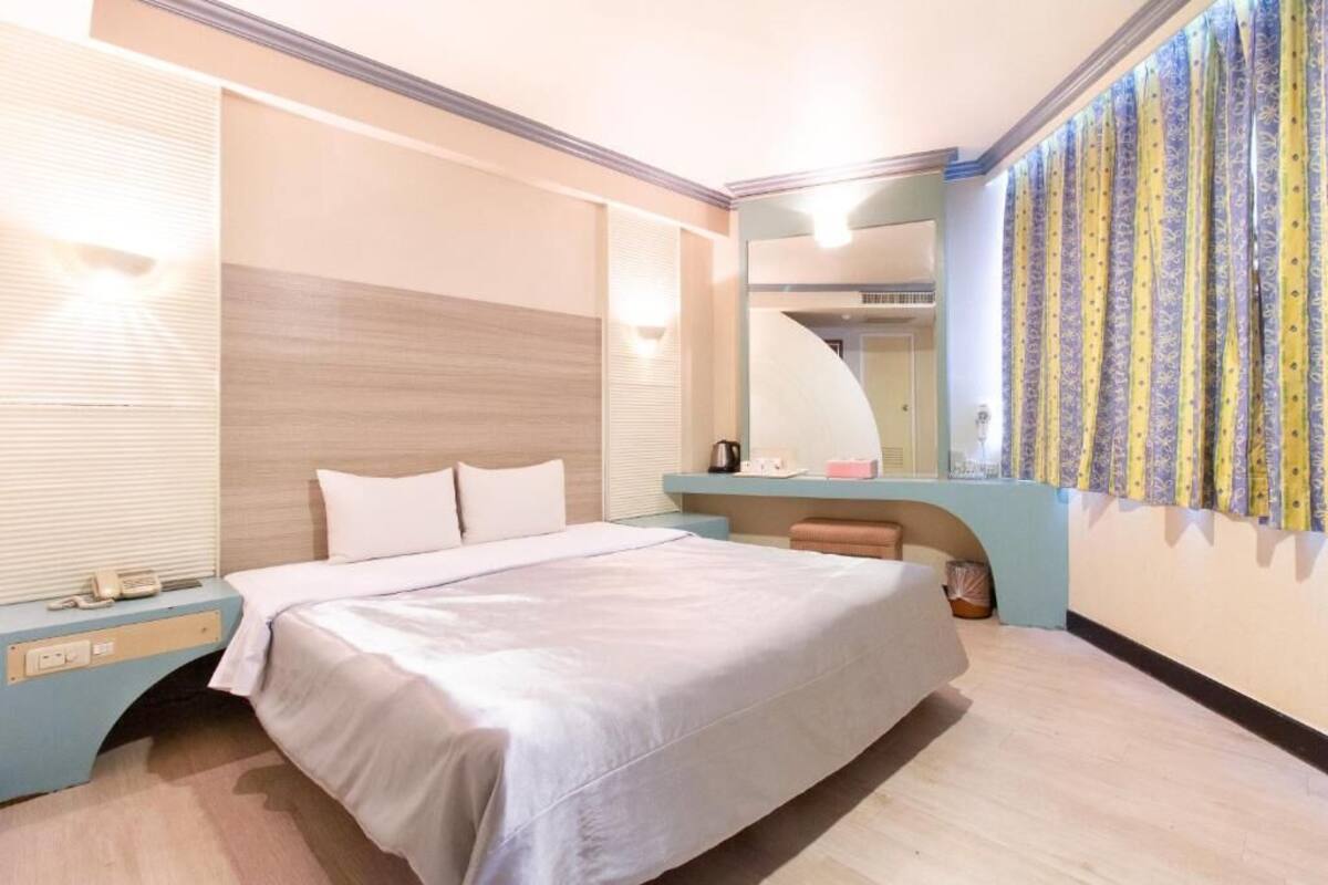 Une chambre à coucher avec un lit, une table de chevet et un miroir.