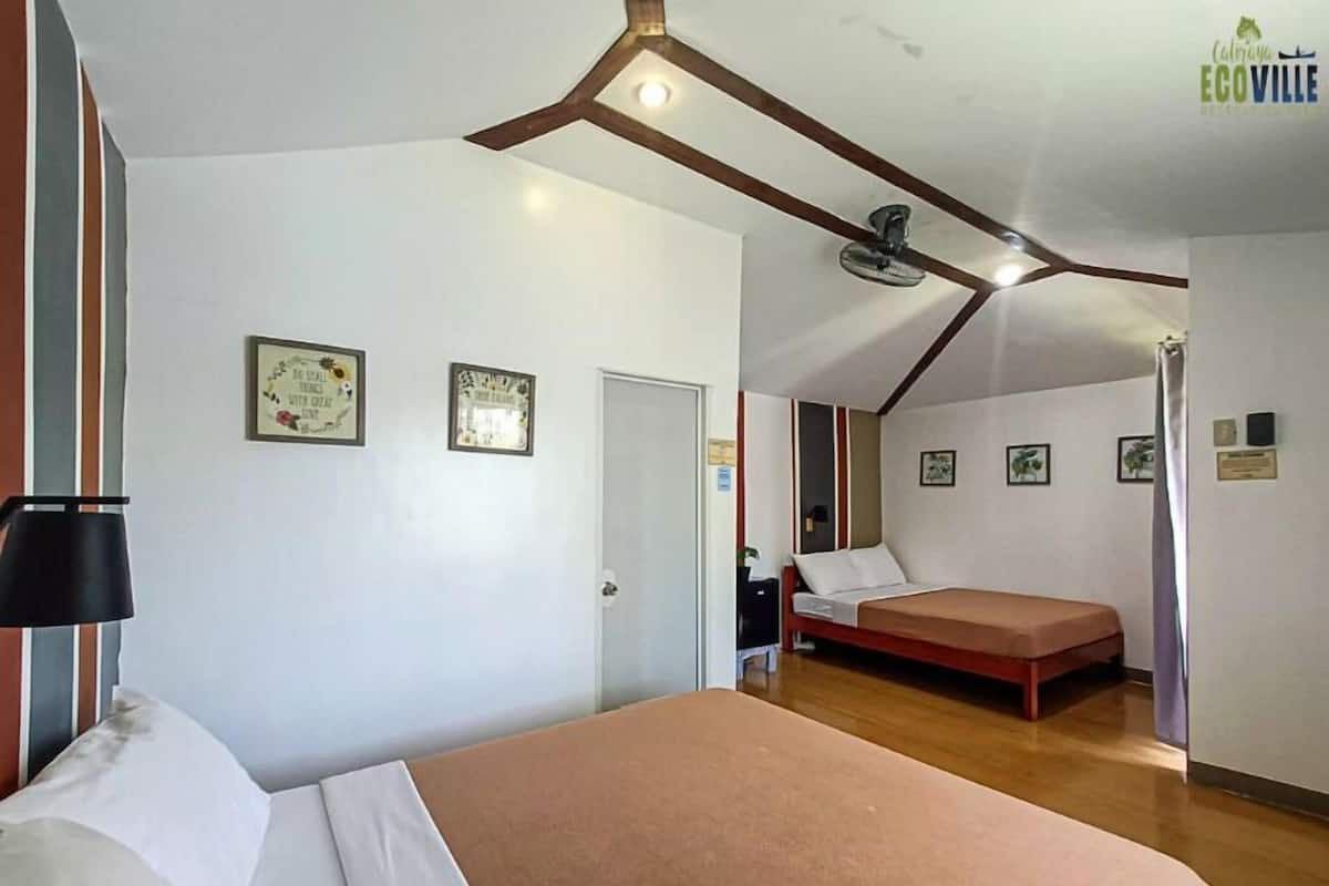 Une chambre à coucher avec un lit, un bureau et une chaise. Deux tableaux encadrés sont accrochés au mur.