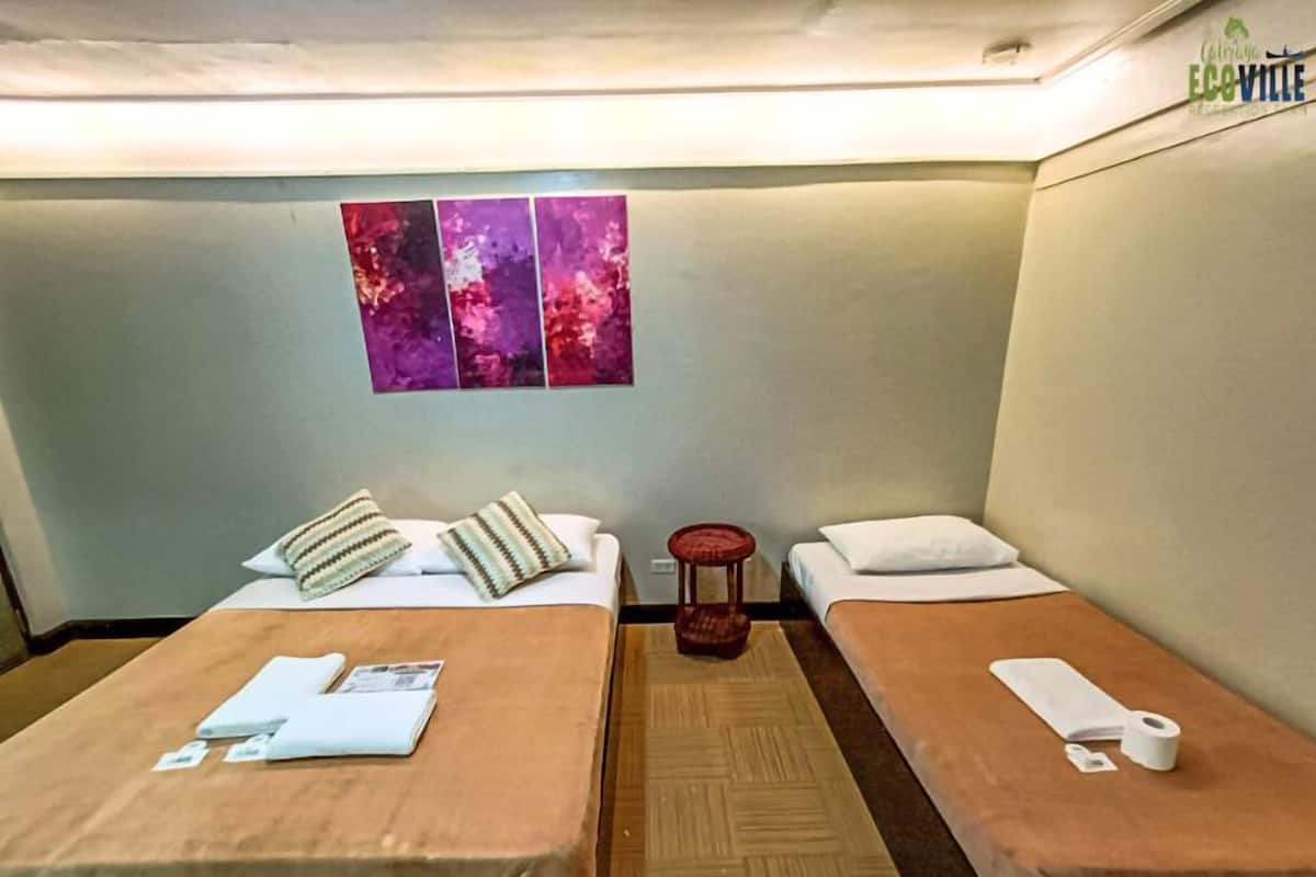 Une chambre d’hôtel avec deux lits, une petite table et un mur orné de trois œuvres d’art.