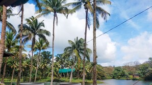 A table with two white cups and saucers, overlooking a lake with palm trees and a hammock. - Caliraya Ecoville Recreation and Farm Resort (Cavinti)