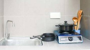 Een keuken met een gootsteen, een fornuis en een pan.