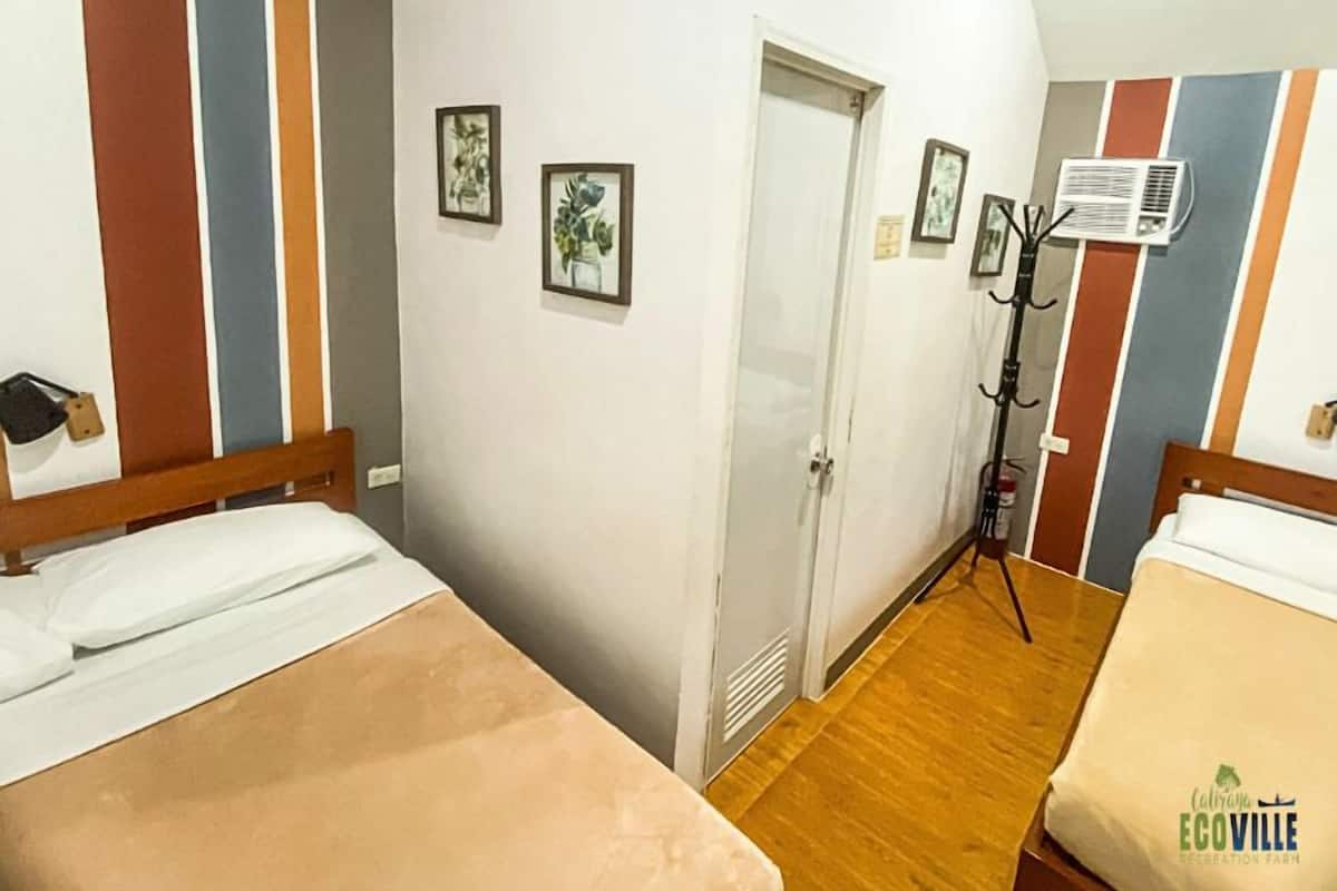 Une chambre d’hôtel avec deux lits, une porte et un porte-manteau.