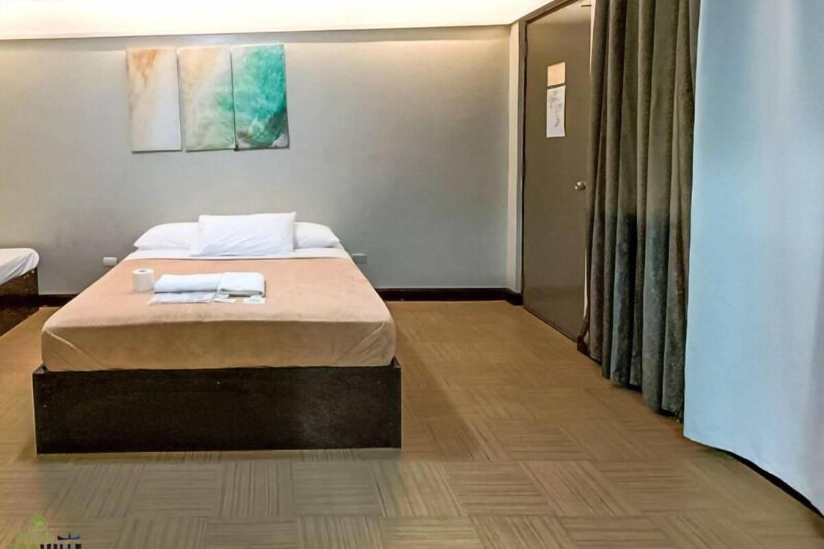 Une chambre d’hôtel avec un lit, une œuvre d’art accrochée au mur, une porte et un rideau.