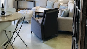 Una sala de estar moderna con un sofá, una mesa de comedor y un televisor montado en la pared.