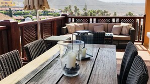 Una mesa de madera con un candelabro de vidrio y una silla de fibras naturales.