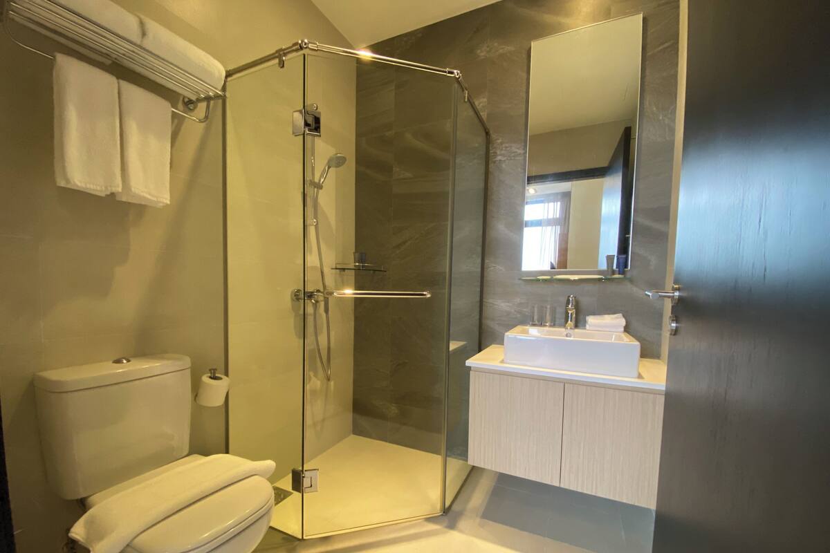 A modern bathroom with a glass-enclosed shower, a white toilet, and a sink with a mirror above it.
