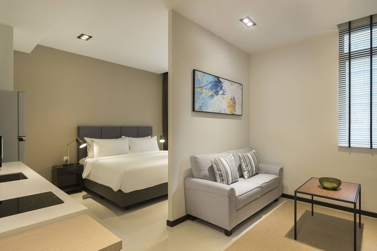 A modern bedroom with a bed, bedside table, and a small table with a bowl.