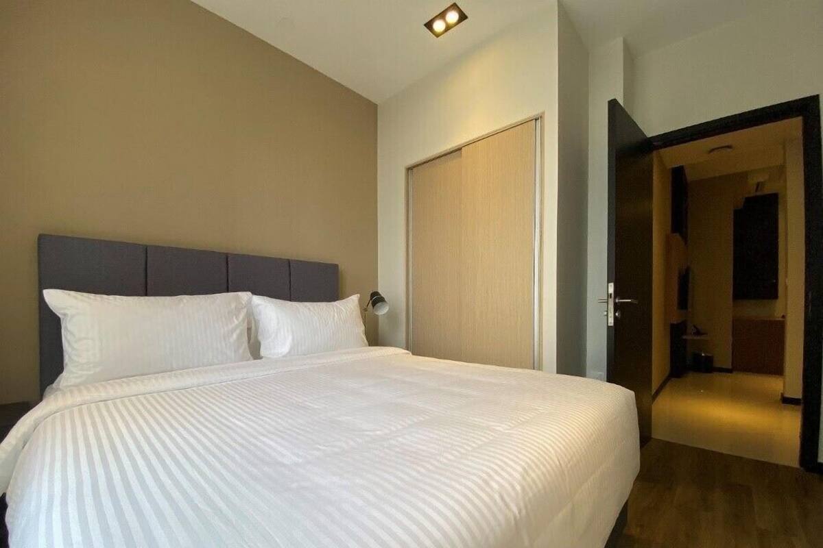 A neatly made bed with white linens in a hotel room.