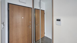 Ein Zimmer mit zwei Holztüren, einem Spiegel und einem an der Wand befestigten Thermostat.