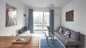 Ein modernes Wohnzimmer mit einer Couch, einem Couchtisch und einem Esstisch mit Frühstücksleckereien.