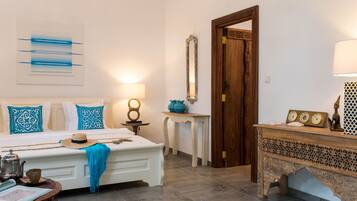 Un dormitorio con cama, mesita de noche, lámpara y objetos decorativos.
